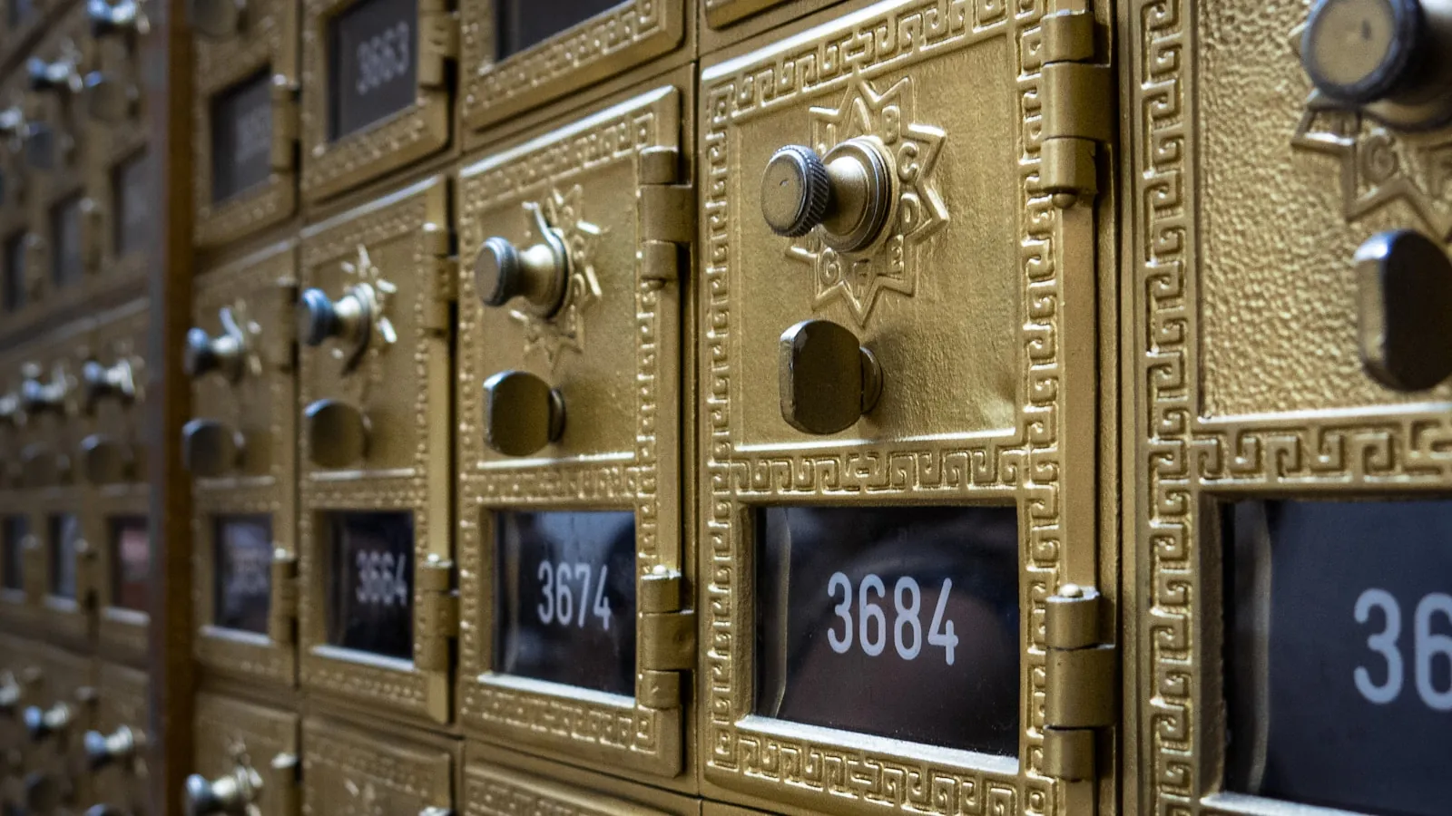 A row of numbered brass post office boxes, each one closed